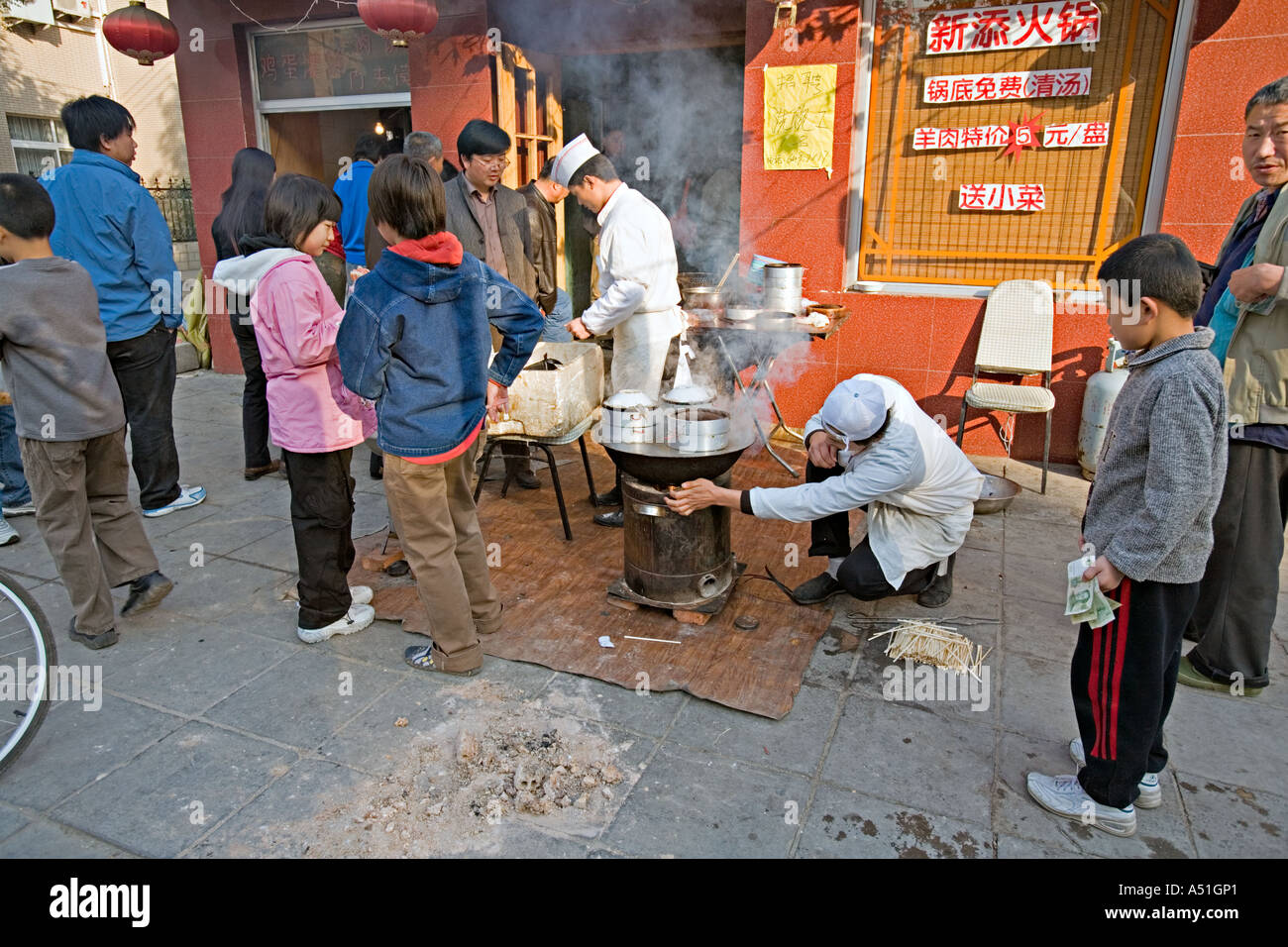 Chine Pékin petit mais occupé restaurant du quartier avec des chefs mis en place sur le trottoir pour préparer le petit déjeuner quenelles Banque D'Images