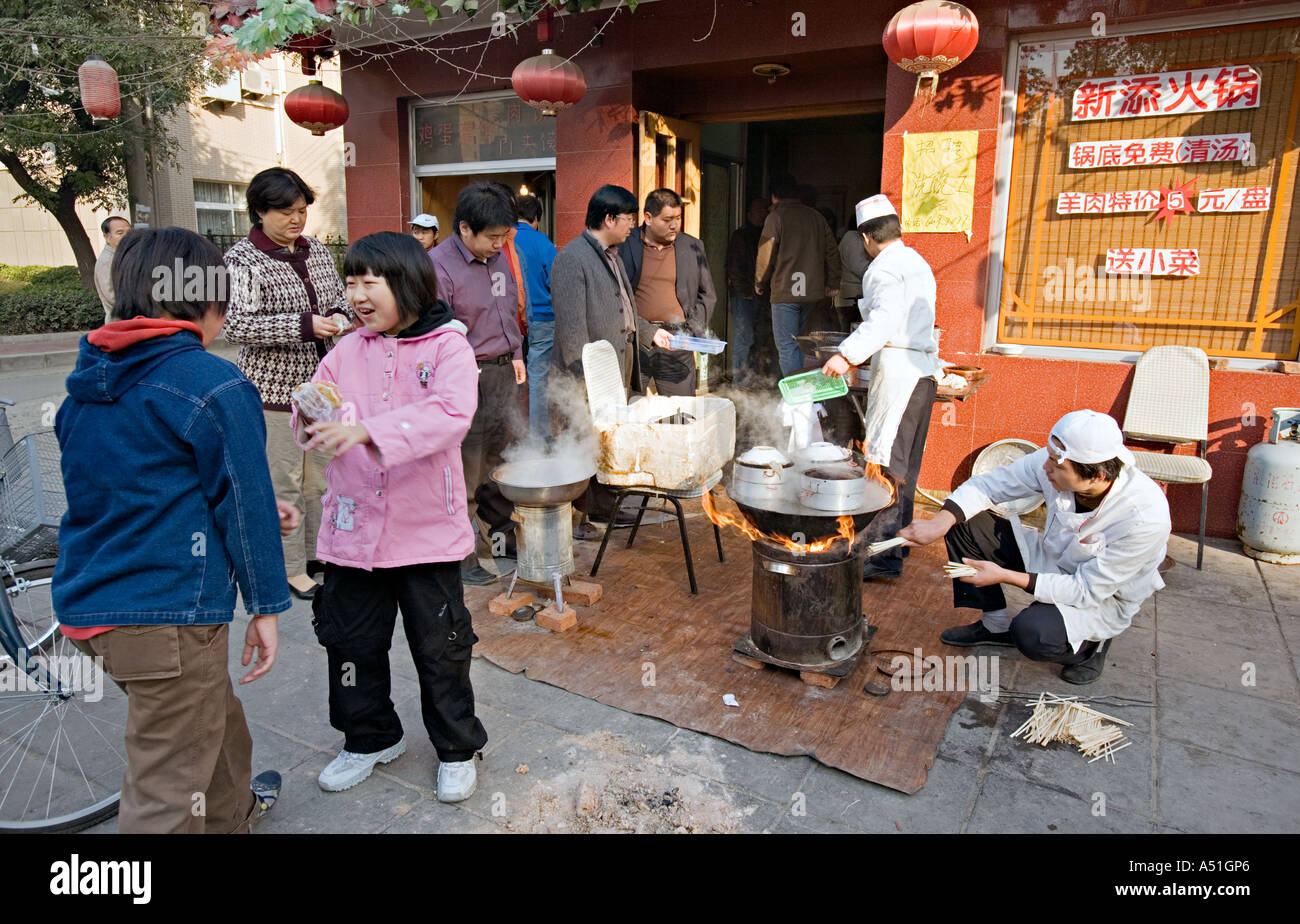 Chine Pékin petit mais occupé restaurant du quartier avec des chefs mis en place sur le trottoir pour préparer le petit déjeuner quenelles Banque D'Images