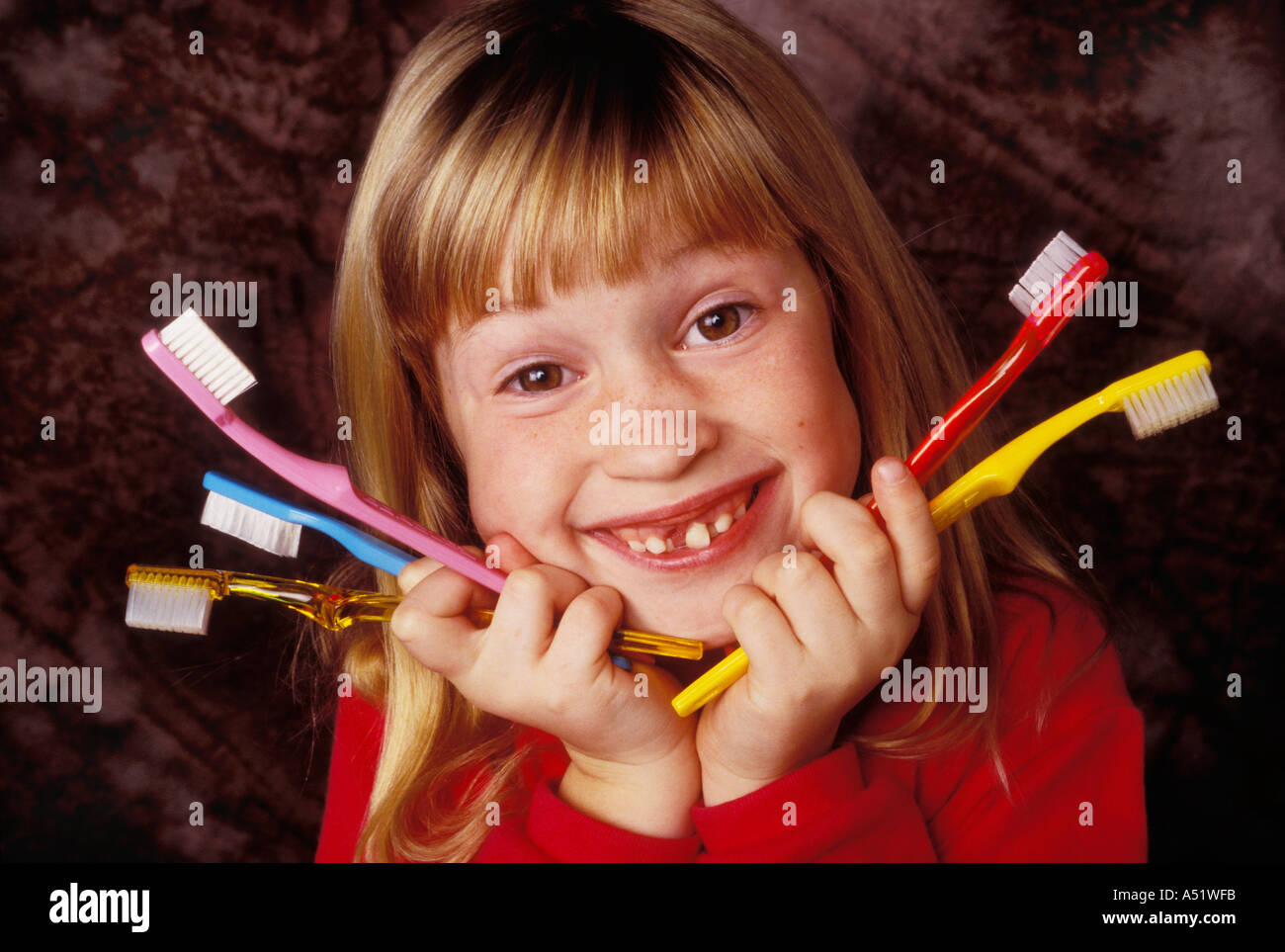 Petite fille manque une dent de devant avec un tas de brosses à dents Banque D'Images