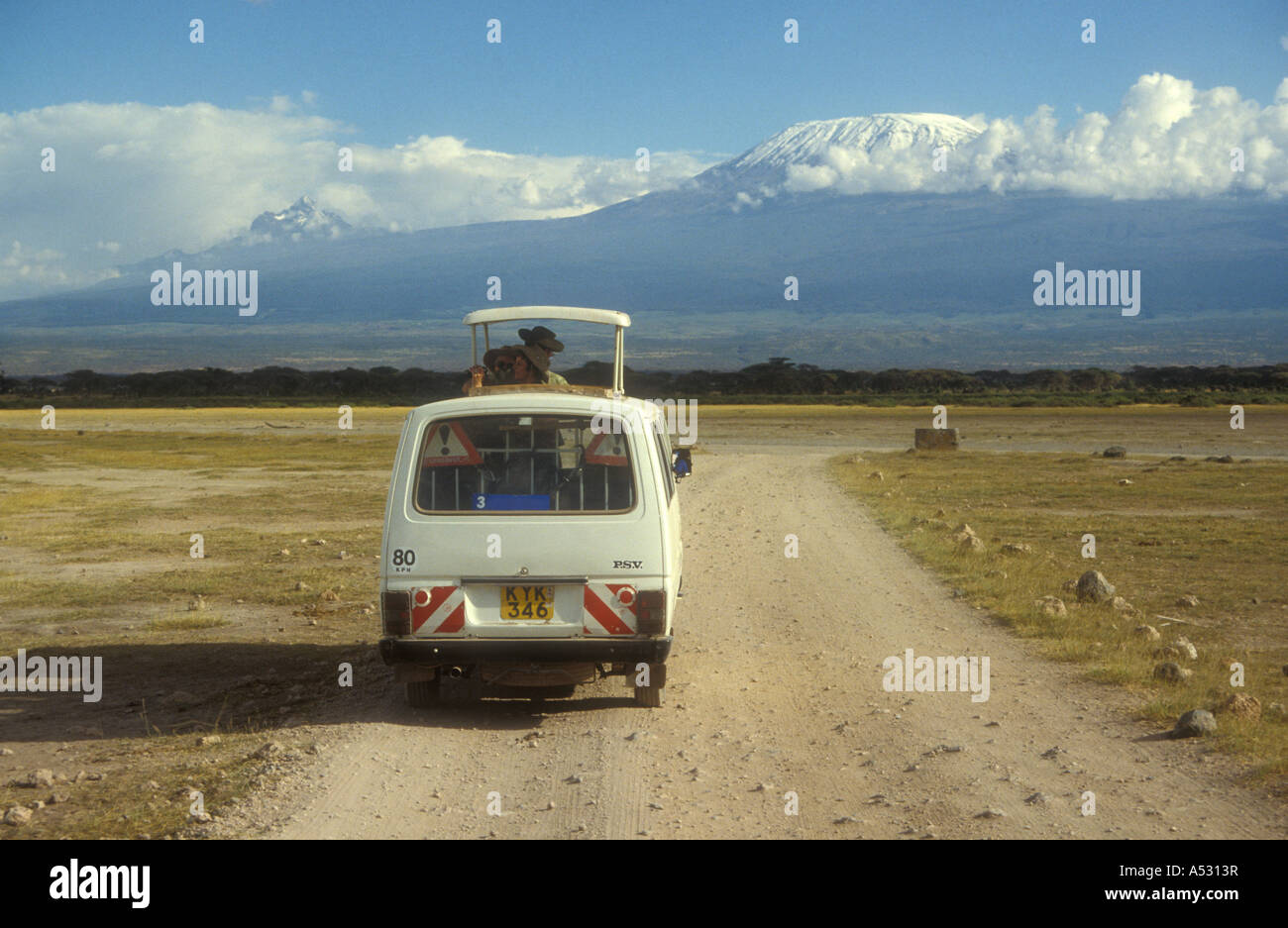 Minibus blanc avec trappe de toit ouvert et les clients en route vers le Kilimandjaro sur un jeu de route du Parc National d'Amboseli au Kenya Banque D'Images