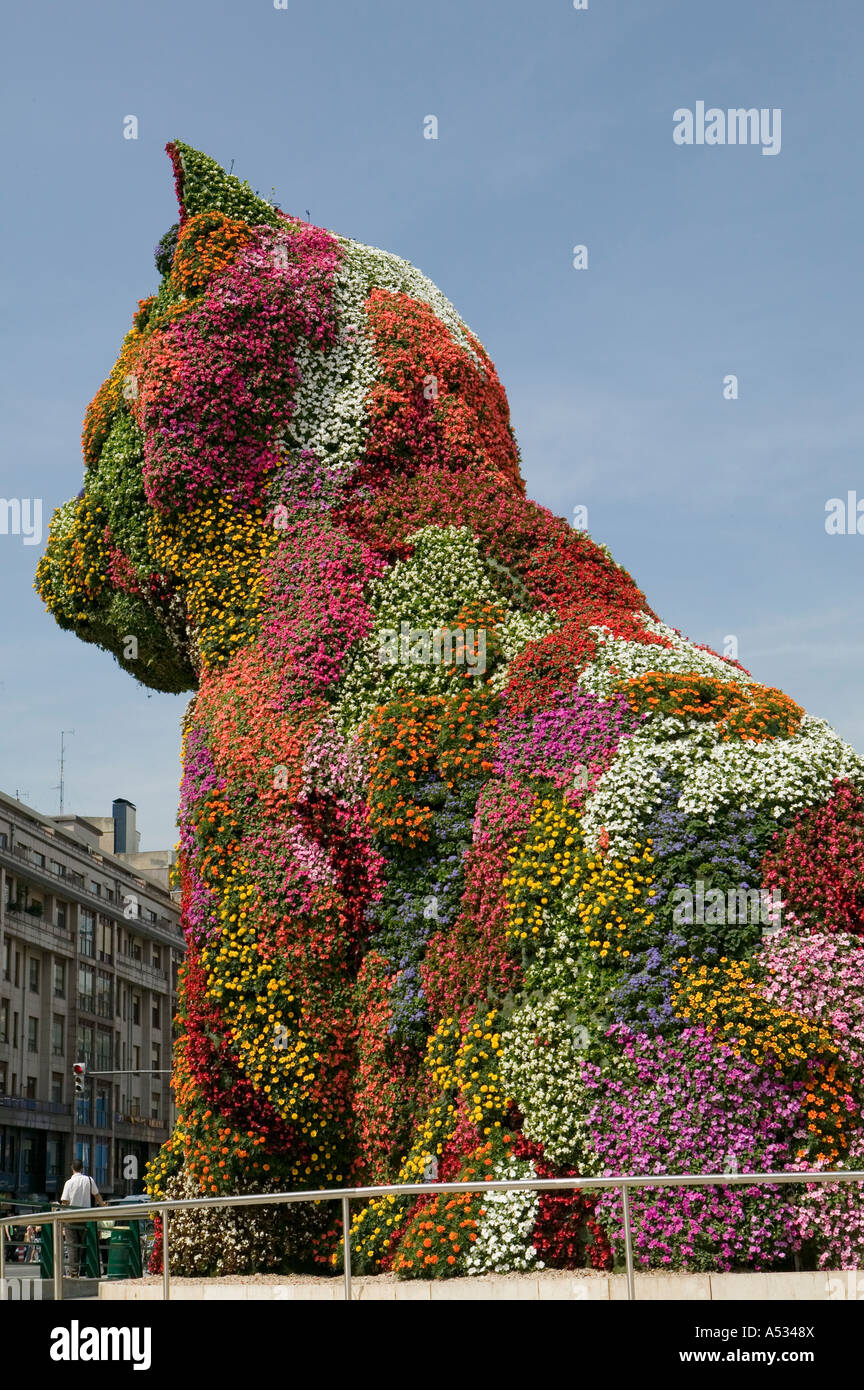 L'homme éclipsé par la taille des topiaires géant de Jeff Koons sculpture 'Chiot' à l'extérieur du musée Guggenheim de Bilbao Banque D'Images