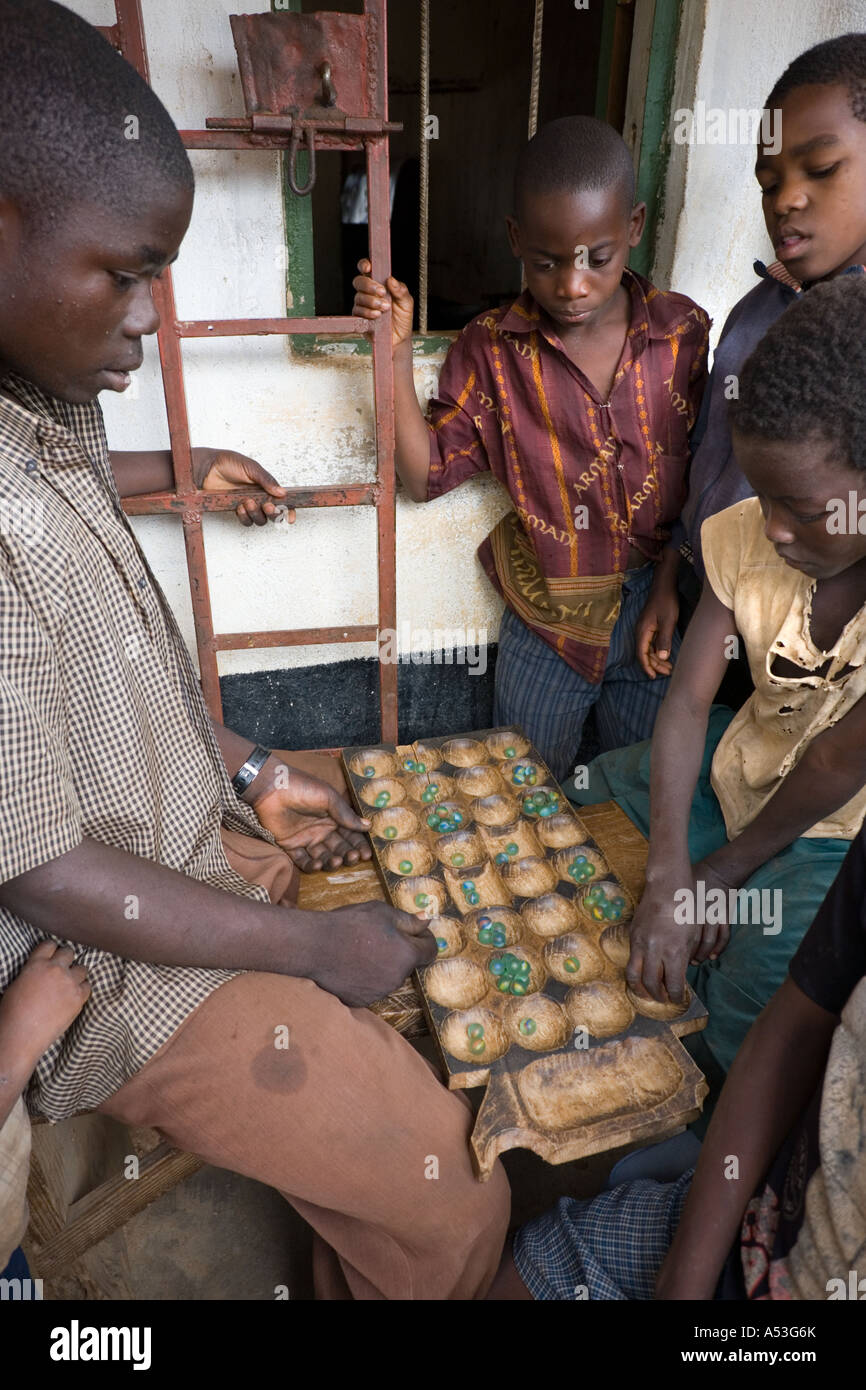 Jouer un jeu de bawo (mancala) à l'extérieur de l'épicerie et salon de thé dans le village de Buli, Malawi, Afrique Banque D'Images