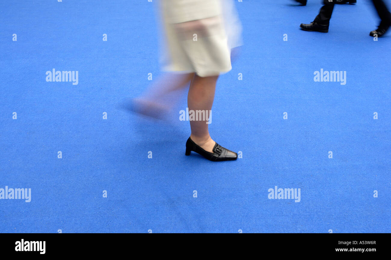 Les jambes de personnes marchant sur un tapis bleu Banque D'Images