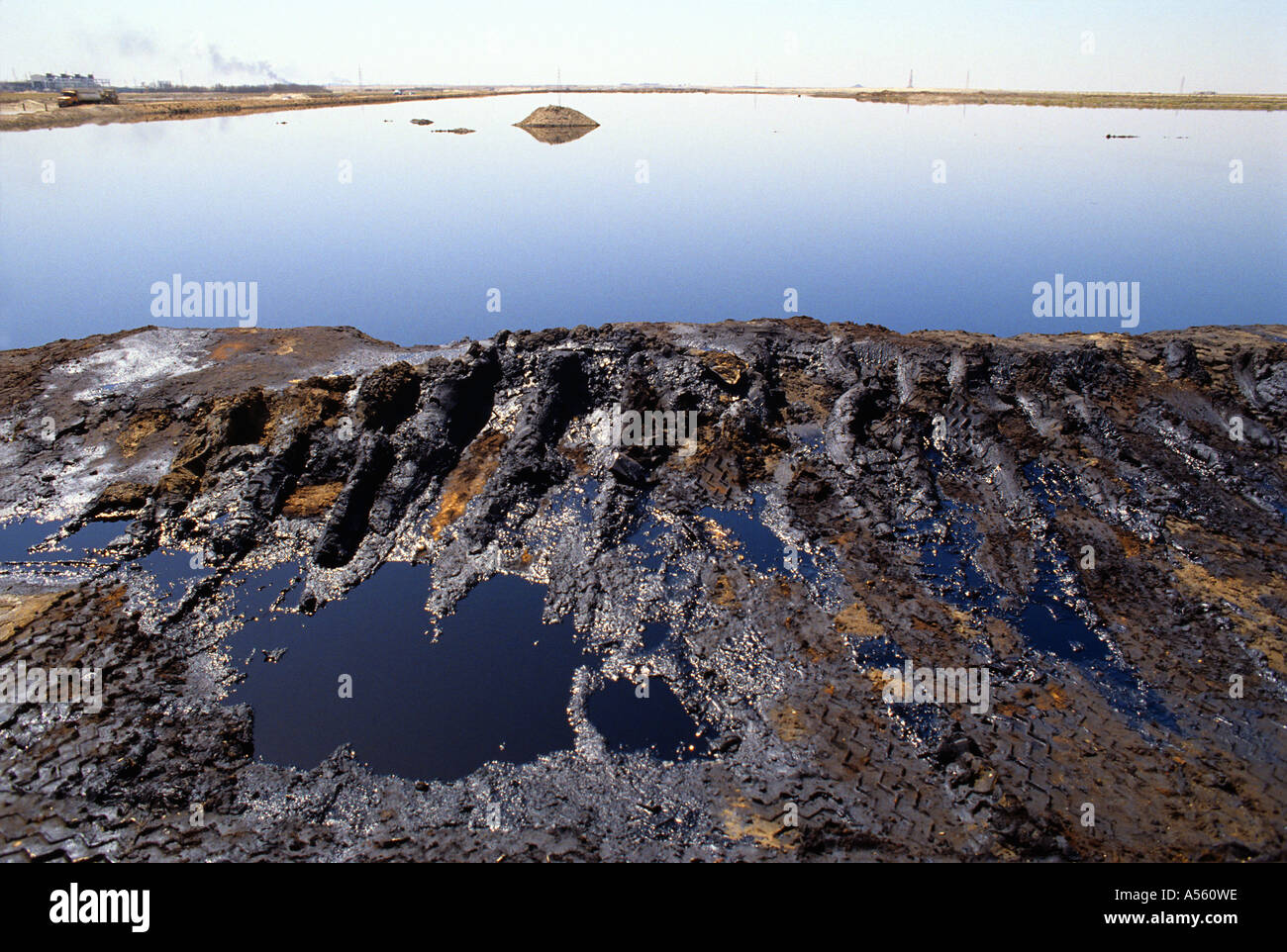 Les traces de pneus dans la boue à côté de vaste lac d'huile au Koweït Banque D'Images