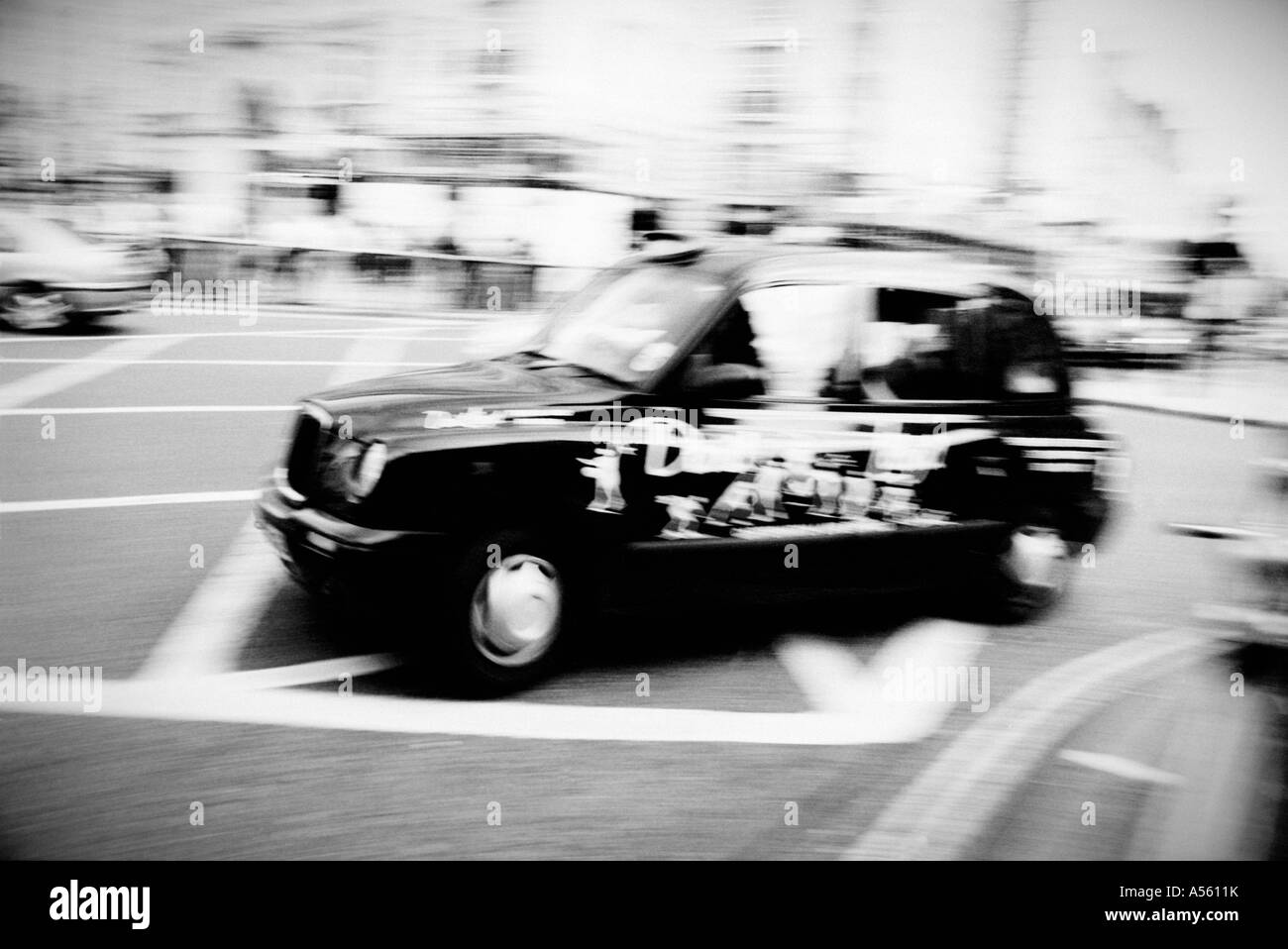 Photo dynamique en noir et blanc montrant un taxi noir traditionnel en mouvement dans une intersection urbaine animée. Banque D'Images