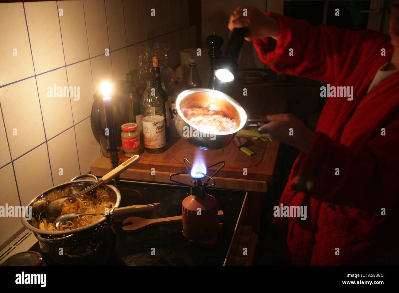 Panne de courant : cookin sur une cuisinière à gaz et de la lumière d'un flambeau Banque D'Images