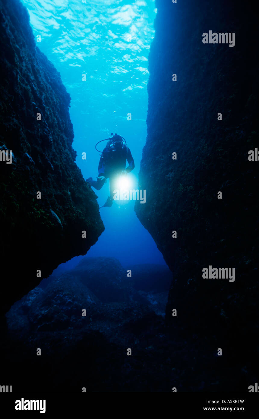 Plongeur sous-marin jette un éclairage tout en nageant à travers une grotte. Banque D'Images