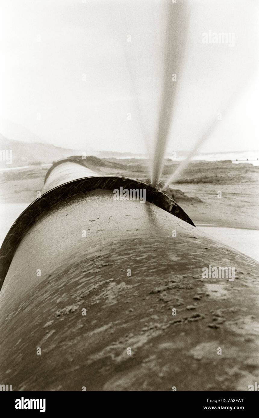 Image en noir et blanc teinté d'eau débordant hors de joint de tuyau. Banque D'Images