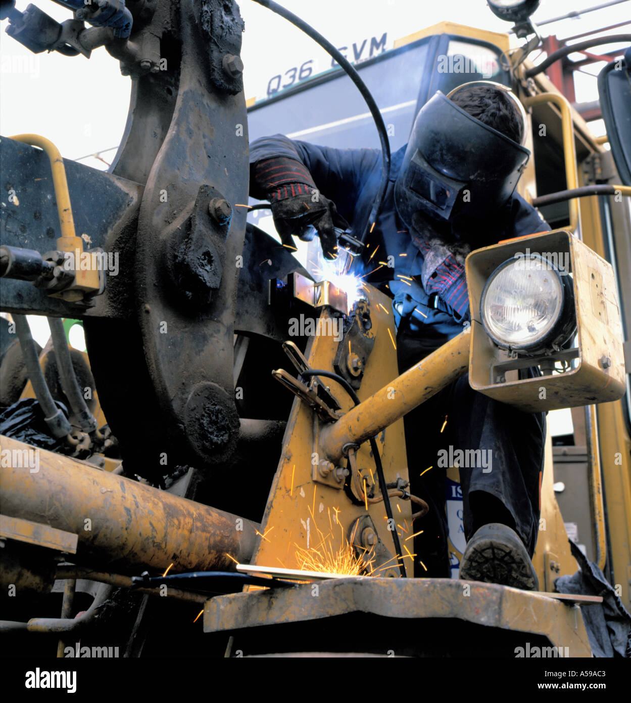 Le soudage d'un homme sur le support d'un chargeur sur roues, England, UK. Banque D'Images