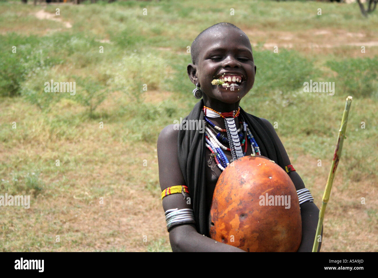Tribu arbore une gourde enfant tenant la canne à sucre, la mastication et chapeau Omo inférieur Valle, Ethiopie Banque D'Images