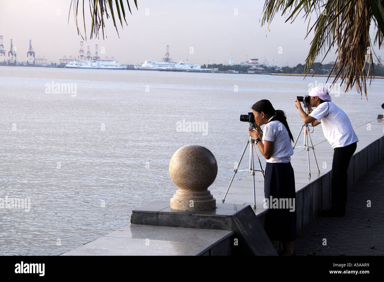 Manille, Philippines, Manila Baywalk, étudiants photographier le coucher de soleil sur la baie Banque D'Images