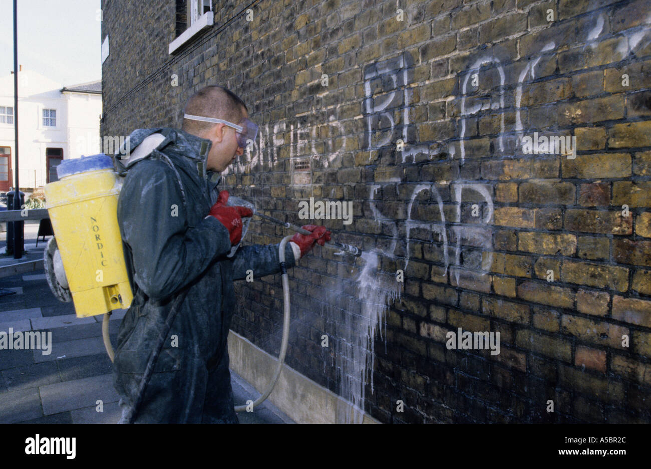 Entrepreneur Conseil enlever des graffitis sur un mur en Greenwich London, England, UK Banque D'Images