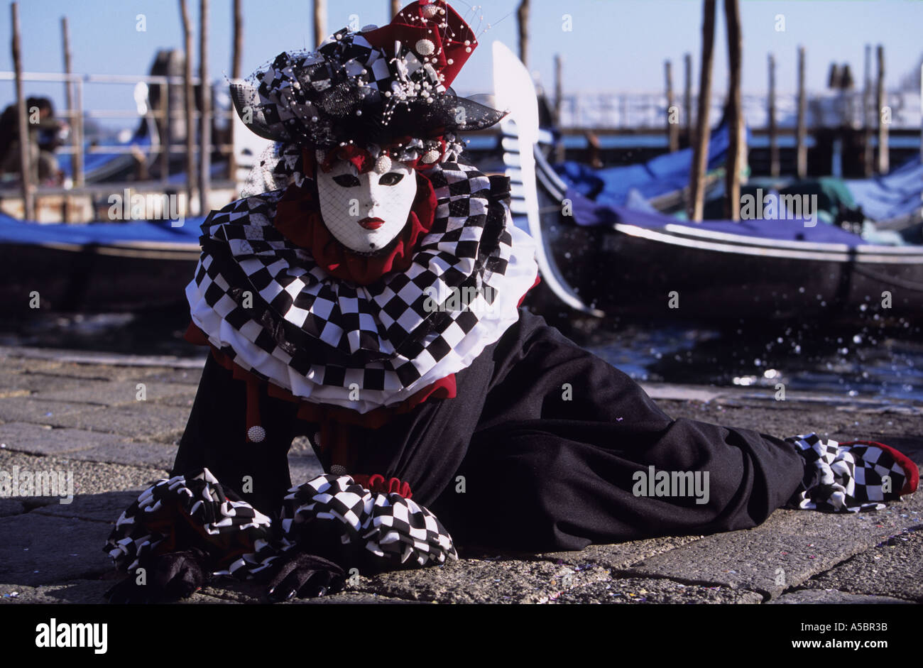 Personnage de carnaval vénitien couché au bord du canal à Venise Italie Banque D'Images