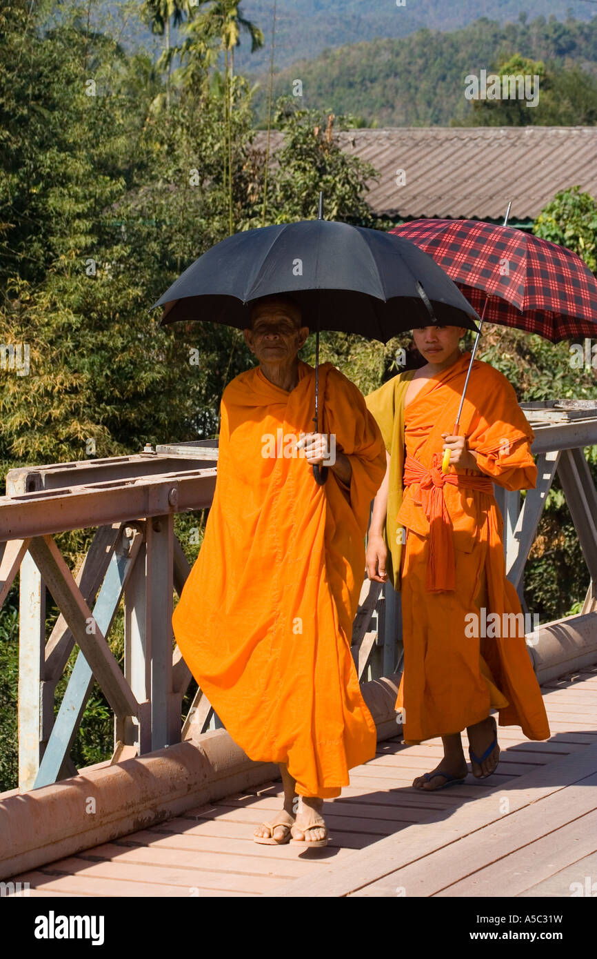 Vieux et jeune moine marchant avec parasols Hongsa Laos Banque D'Images