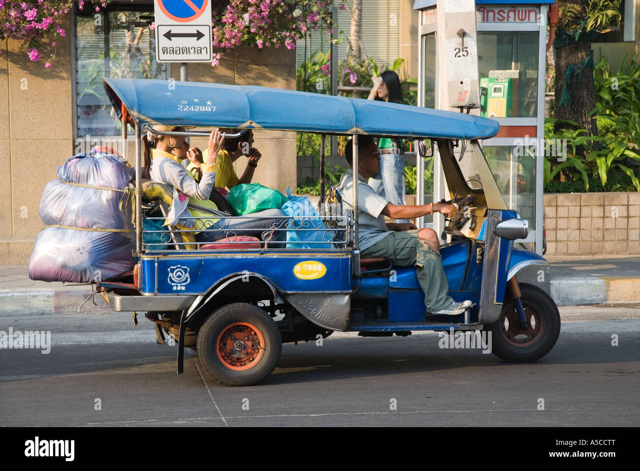Conducteur de tuk-tuks surchargé de taxi à Bangkok, le port de masque à la pollution comme protection contre le smog et les gaz d'échappement des véhicules. Banque D'Images