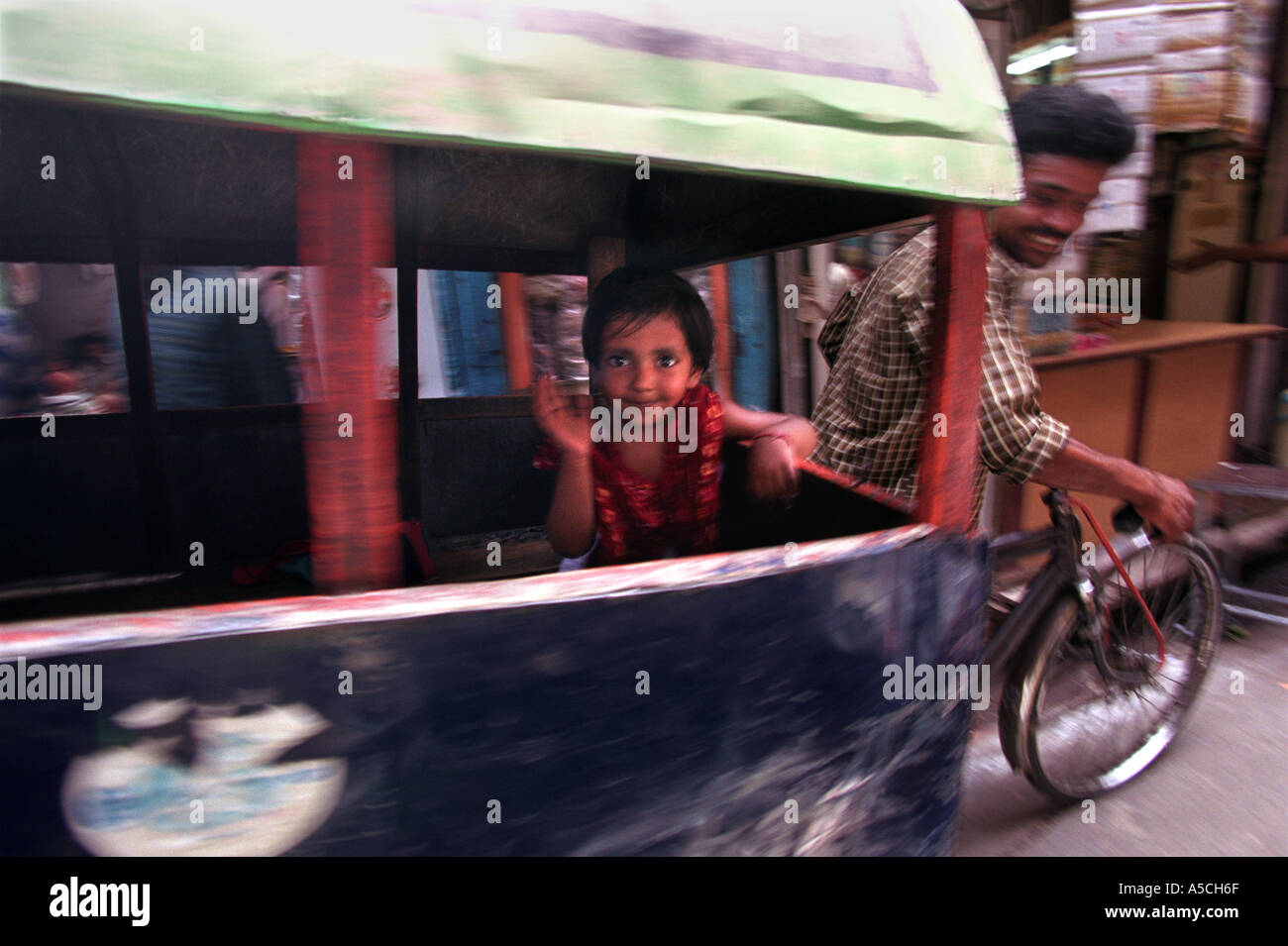 Une petite fille souriante ondes d'un pousse-pousse à vélo dans les ruelles de New Delhi juste à côté de la Chandni Chowk Banque D'Images Une petite fille souriante ondes d'un pousse-pousse à vélo dans les ruelles de New Delhi juste à côté de la Chandni Chowk Banque D'Images