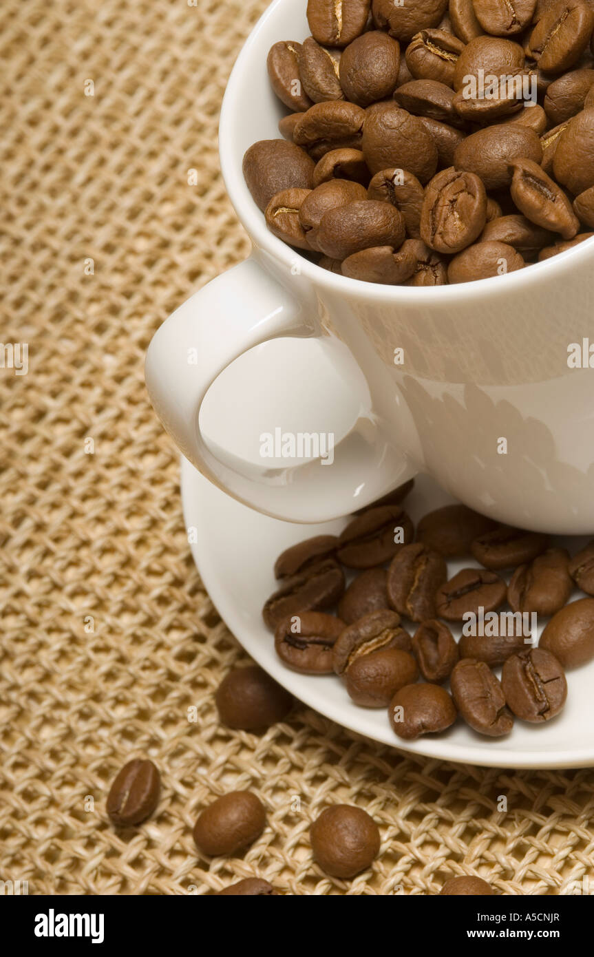 Gros plan des grains de café dans une tasse et une soucoupe Banque D'Images