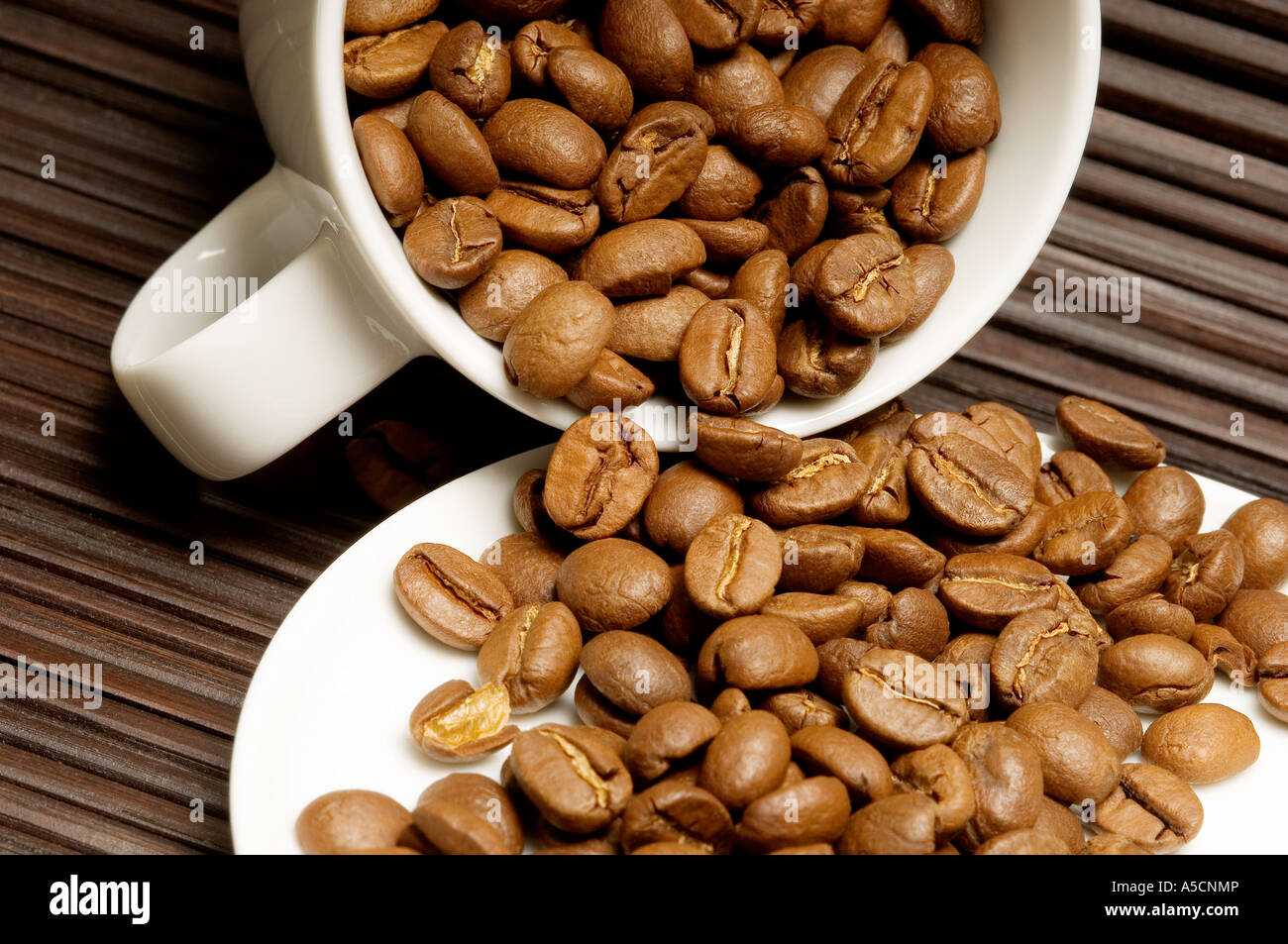 Gros plan des grains de café dans la tasse qui se déverse sur la soucoupe Banque D'Images