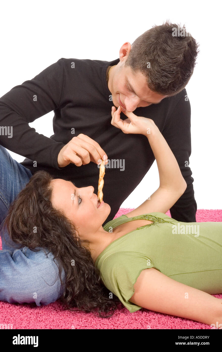 Jeune couple nourrir chaque autre rouleau cake fond blanc Banque D'Images