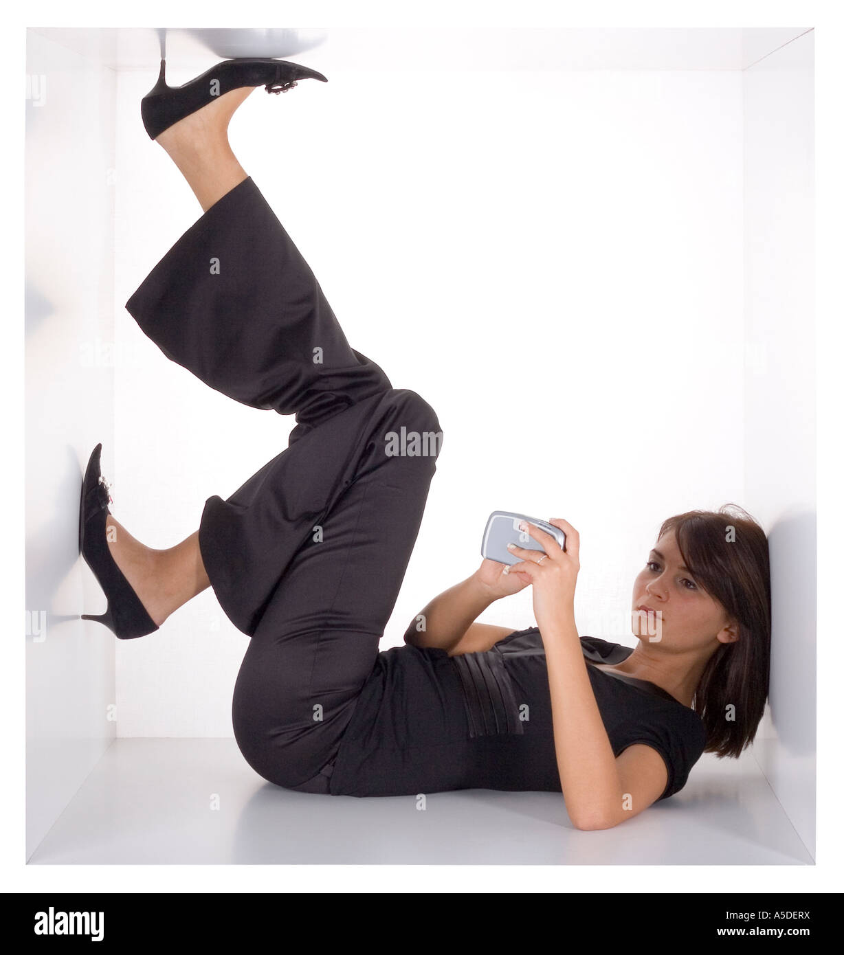 Businesswoman avec téléphone mobile de poche dans le white cube étroit Banque D'Images