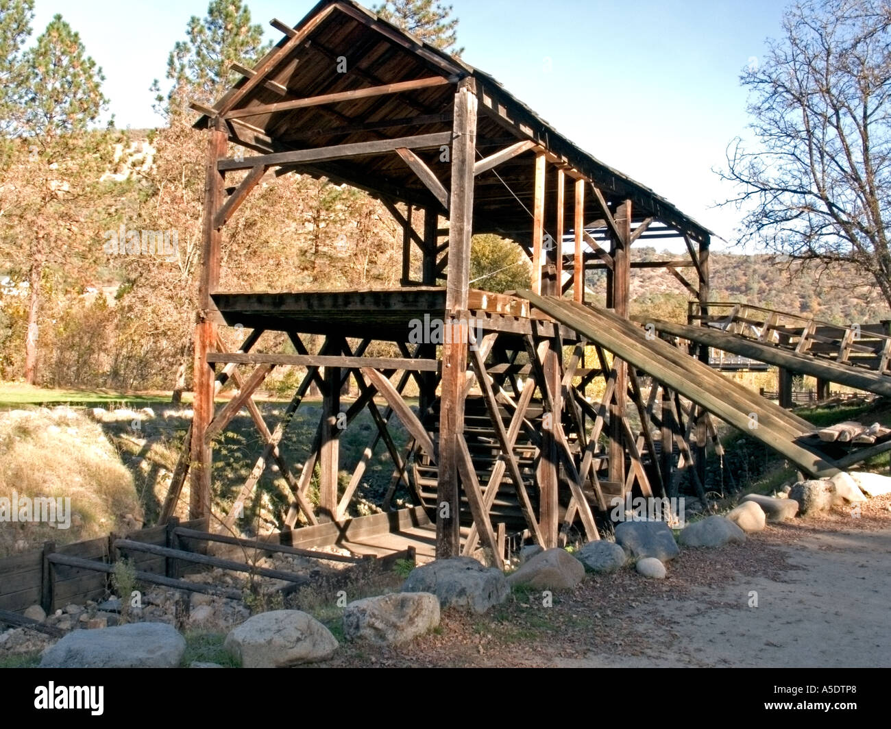 Une reconstruction en bois de Sutter's Mill, le site de découverte de l'or, se dresse près d'arbres et d'un chemin de terre dans le Marshall Gold Discovery State Historic Park. Banque D'Images