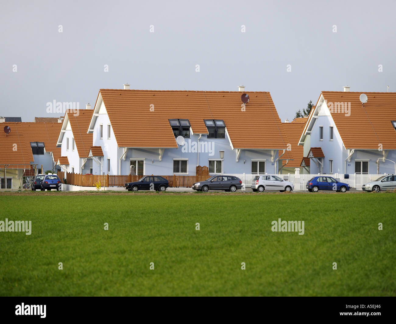 Maisons nouvellement construites dans le pays avec une rangée de voitures en stationnement Banque D'Images