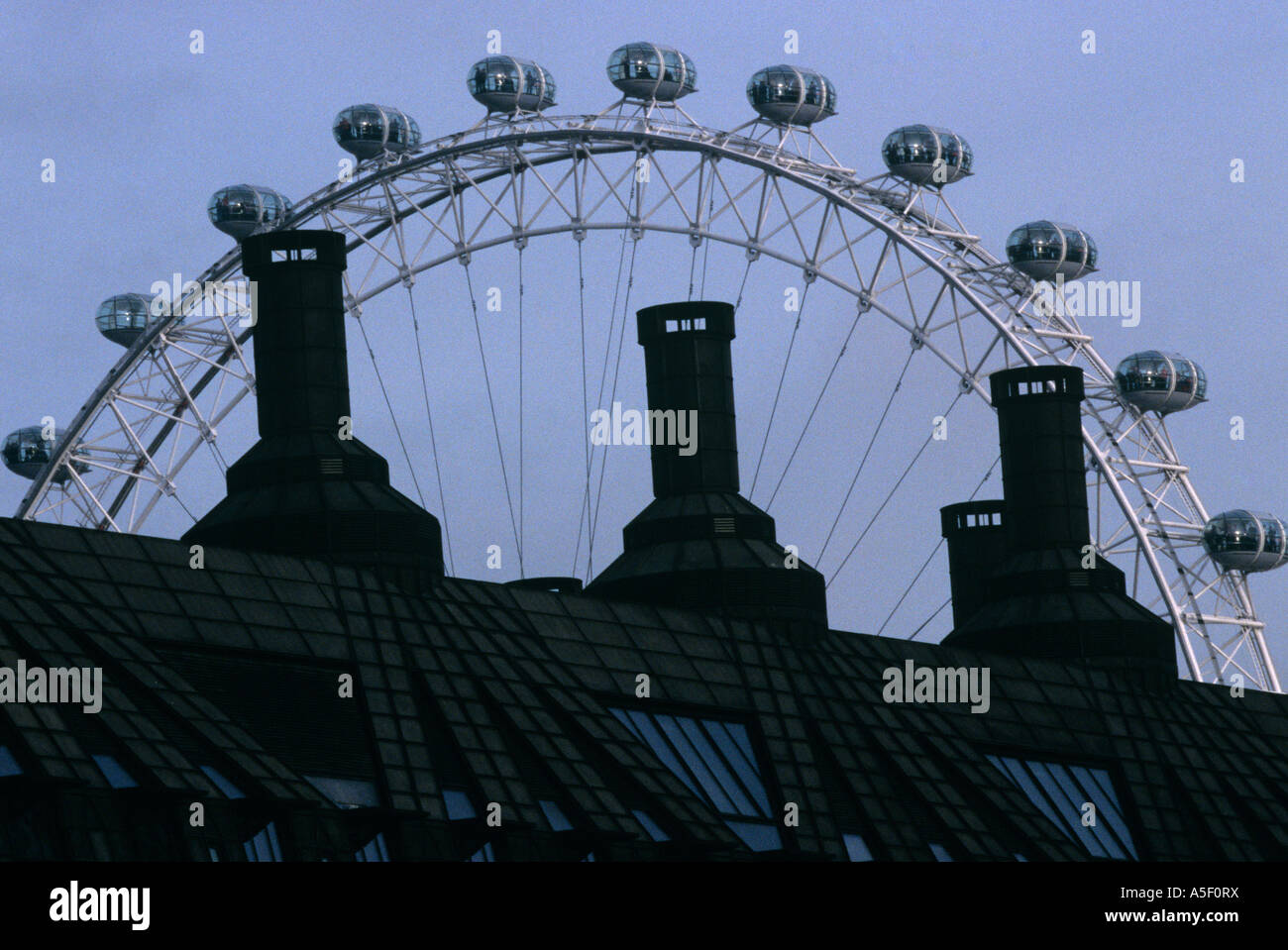 London Eye capsules passager derrière la rangée de silhouetté cheminées, Londres, UK Banque D'Images
