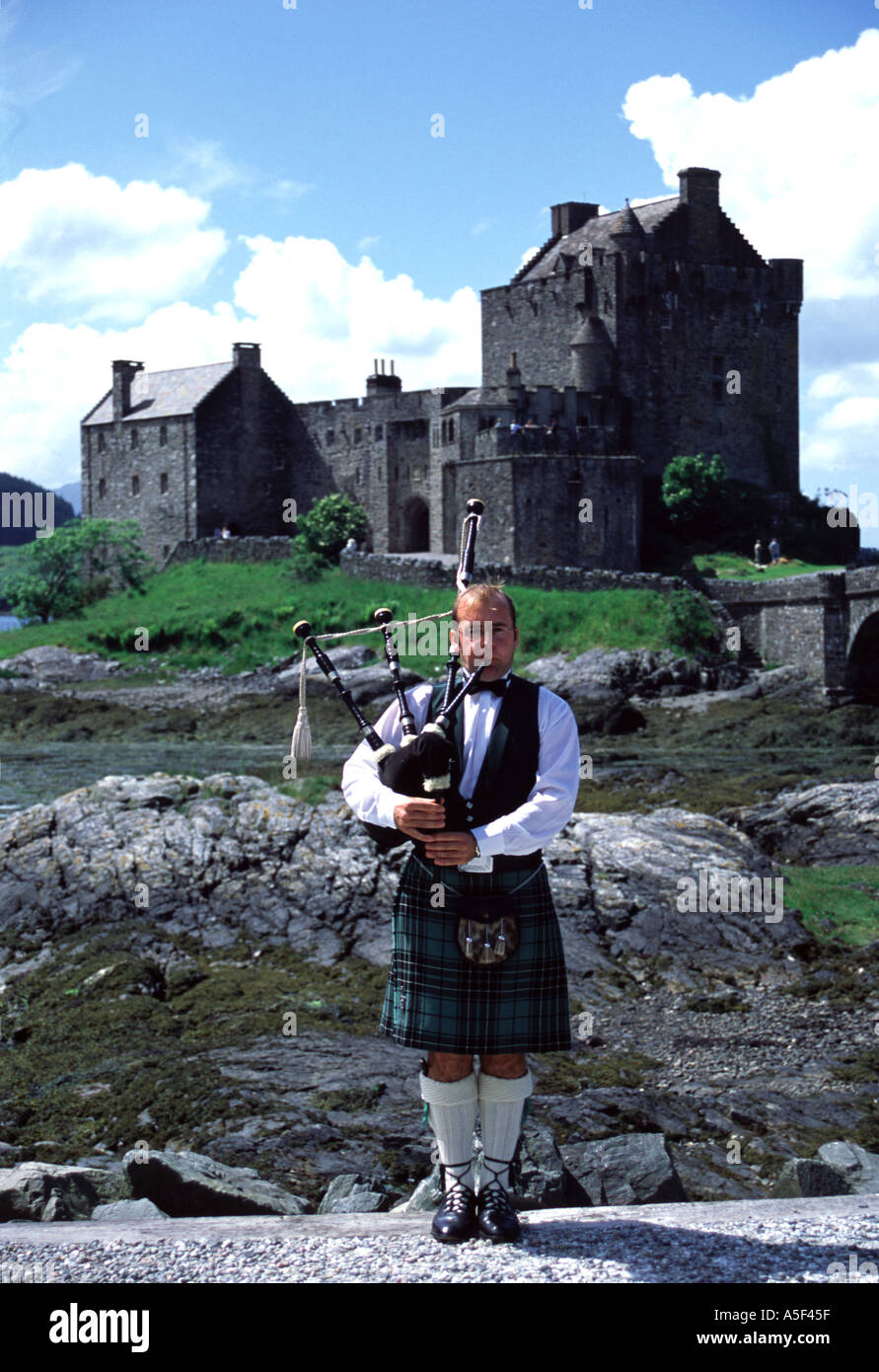 Piper écossais jouer de la cornemuse avec le Château d'Eilean Donan en arrière-plan Banque D'Images