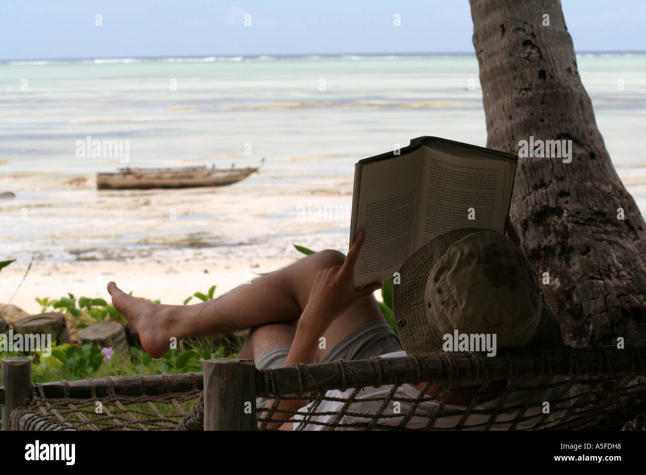 ZANZIBAR : se détendre et lire un livre en face d'une plage de sable blanc sur la côte est, en Tanzanie Banque D'Images