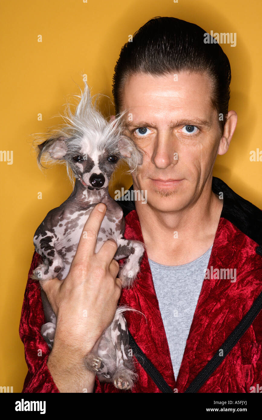 Portrait of mid adult male wearing velvet et holding chien chinois à crête Banque D'Images