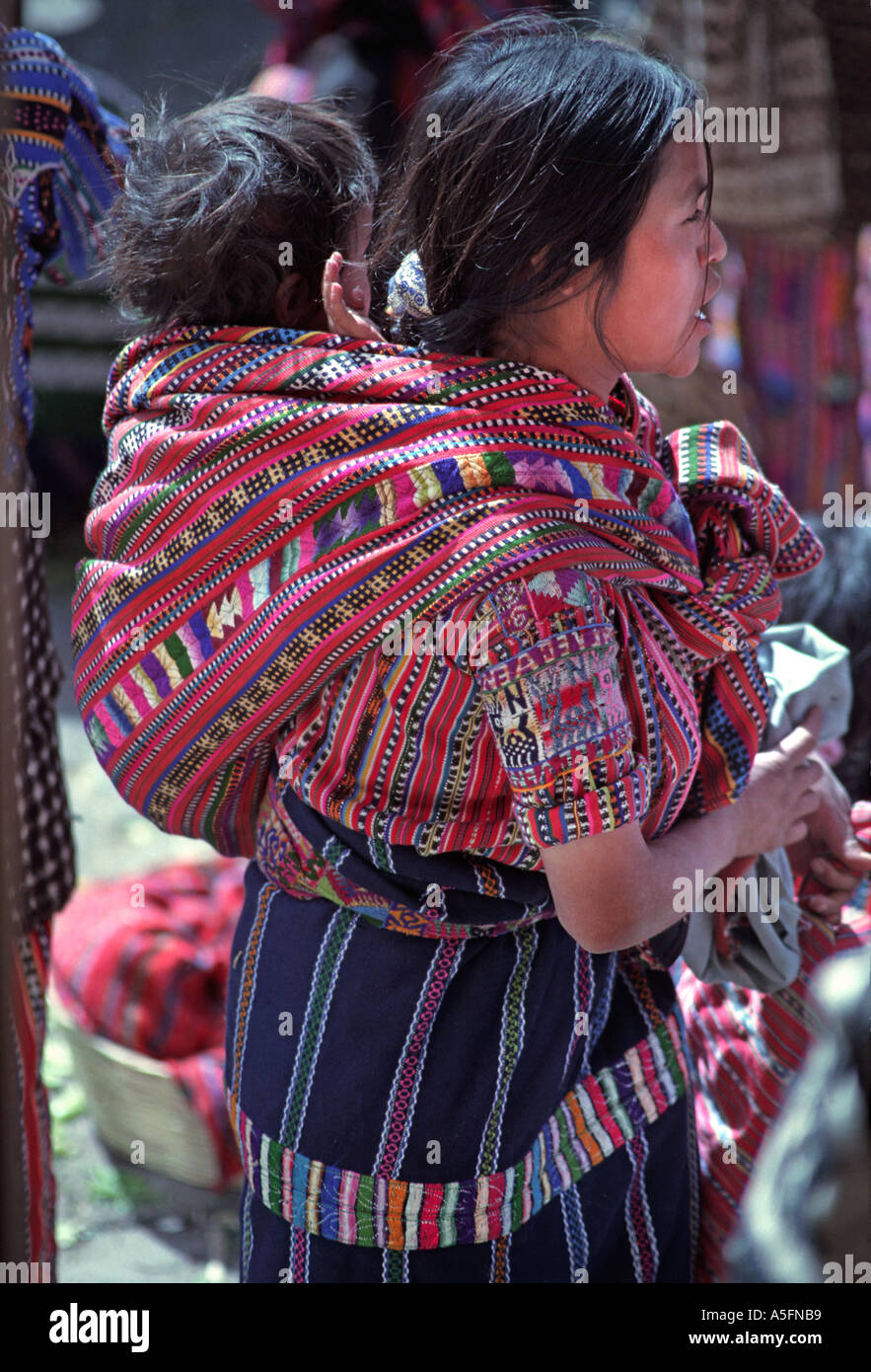 Femme Maya de Solola au port du marché des vêtements à sa communauté exerçant son bébé dans un châle tissé Guatemala Amérique C Banque D'Images