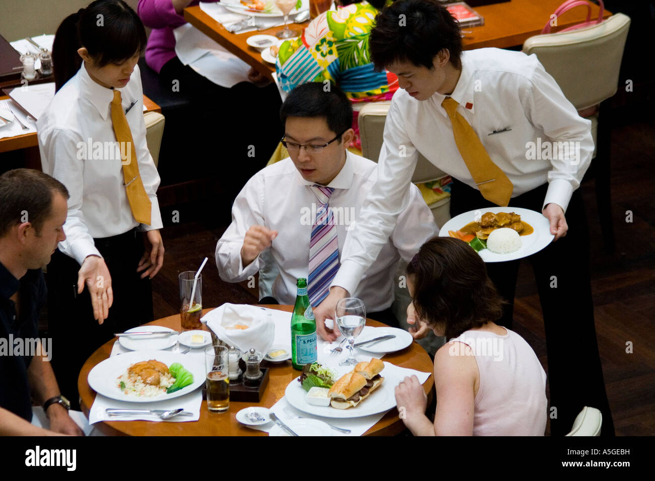 Serveur et serveuse livrer de la nourriture à une clientèle huppée restaurant Hong Kong Banque D'Images