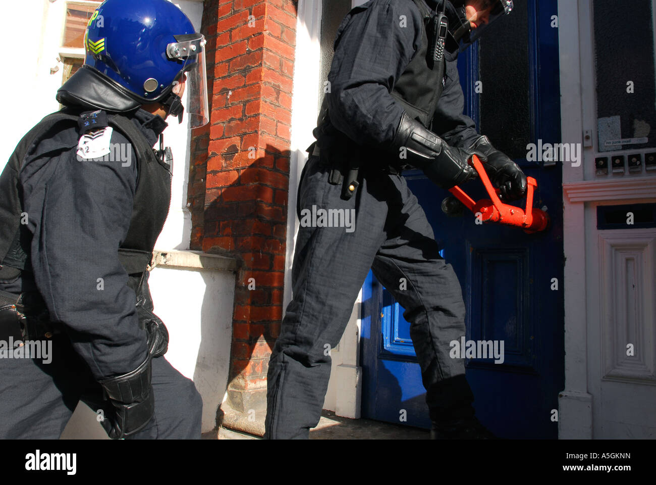 Agent de police au sujet de la pâte vers le bas sur la porte avant d'un raid de crack à Fulham, à l'ouest de Londres, Royaume-Uni. Banque D'Images