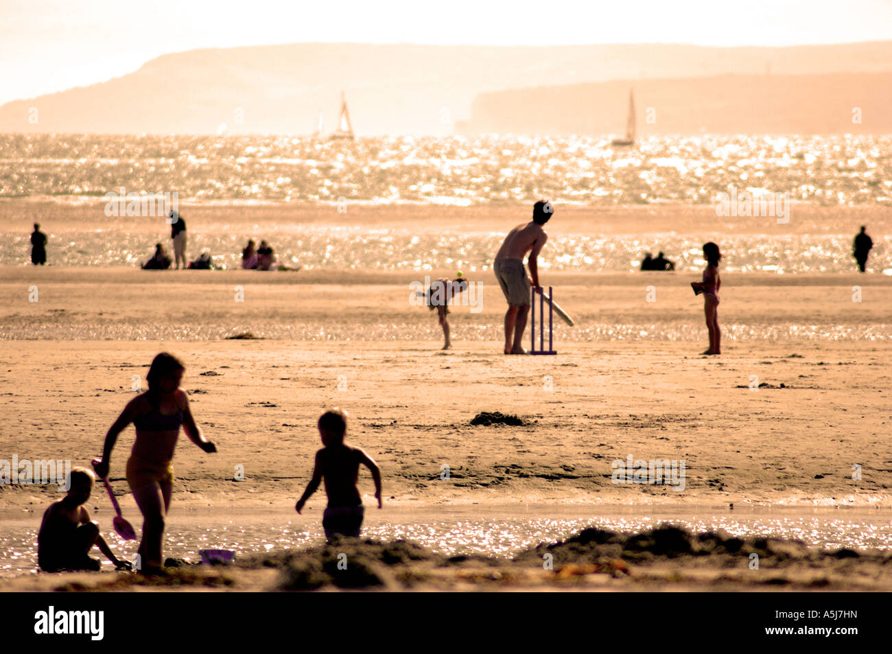 Coucher du soleil sur la plage avec la famille à jouer au cricket UK Banque D'Images