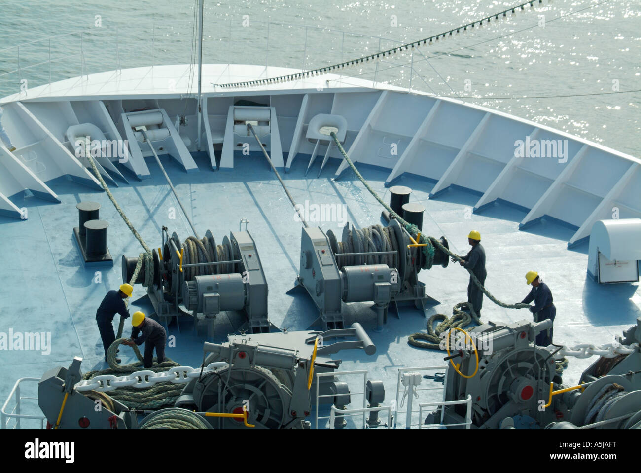 À la vue de dessus vers le bas à l'avant de navire de croisière de passage de l'esprit d'équipe de marins en casque de travail manutention amarres & machines de bobinage Banque D'Images