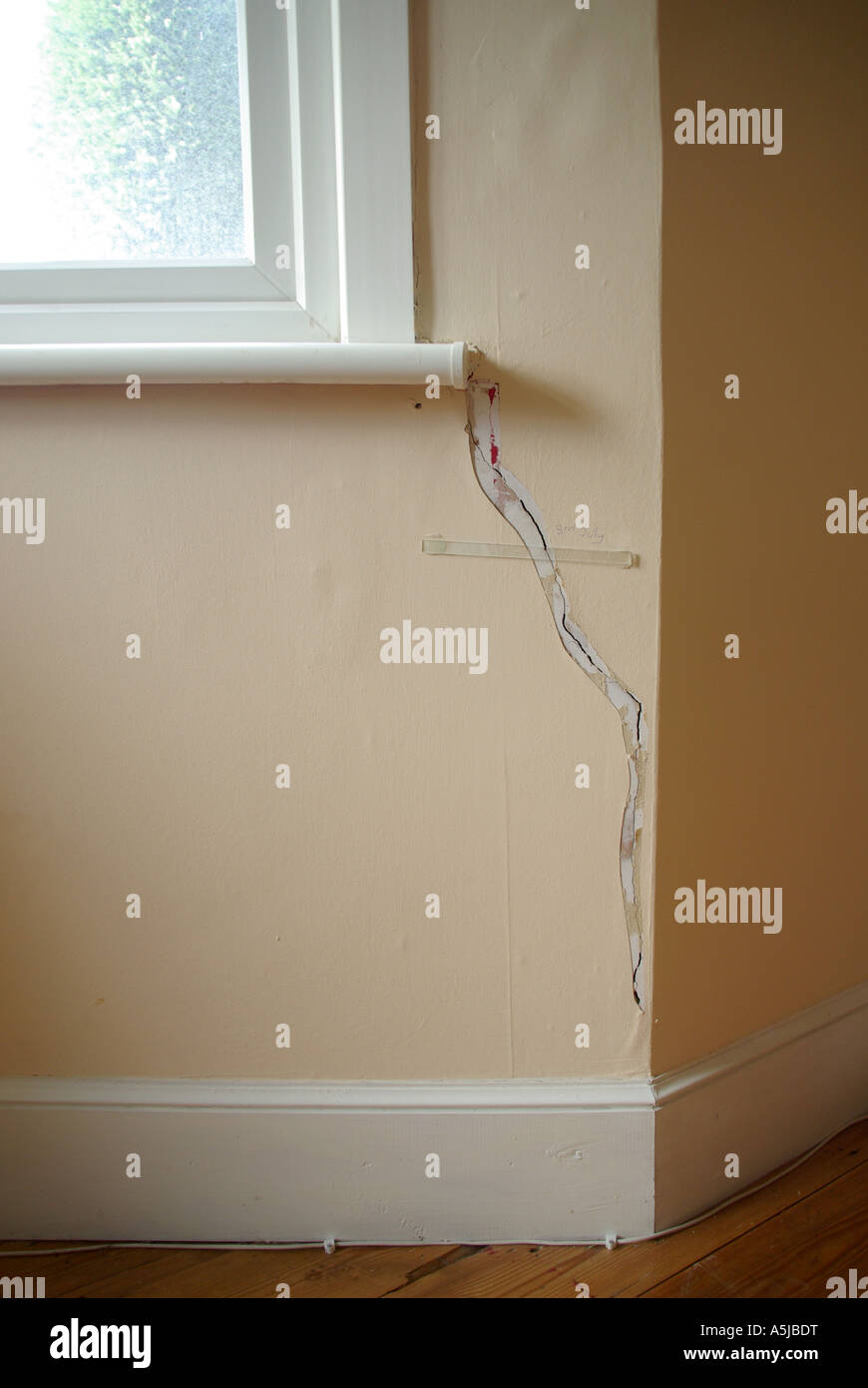 Chambre dommages intérieurs sur mur avec bande de verre collé au crack par compagnie d'assurance afin de surveiller d'autres mouvements Banque D'Images