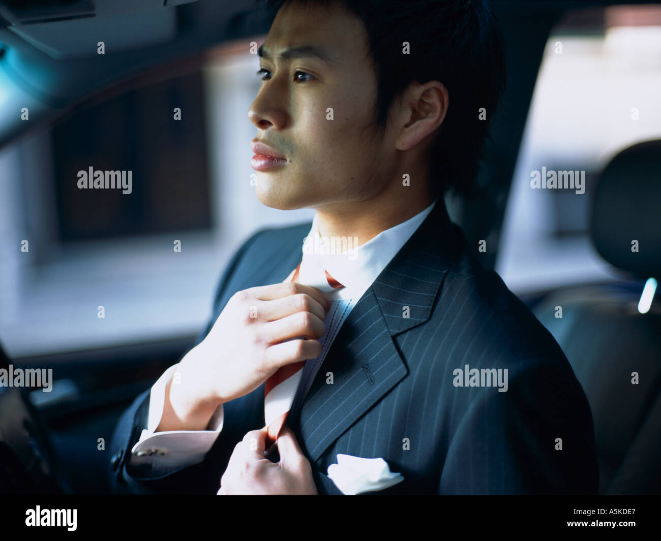 Fixation Homme asiatique sa cravate dans le rétroviseur Photo Stock - Alamy