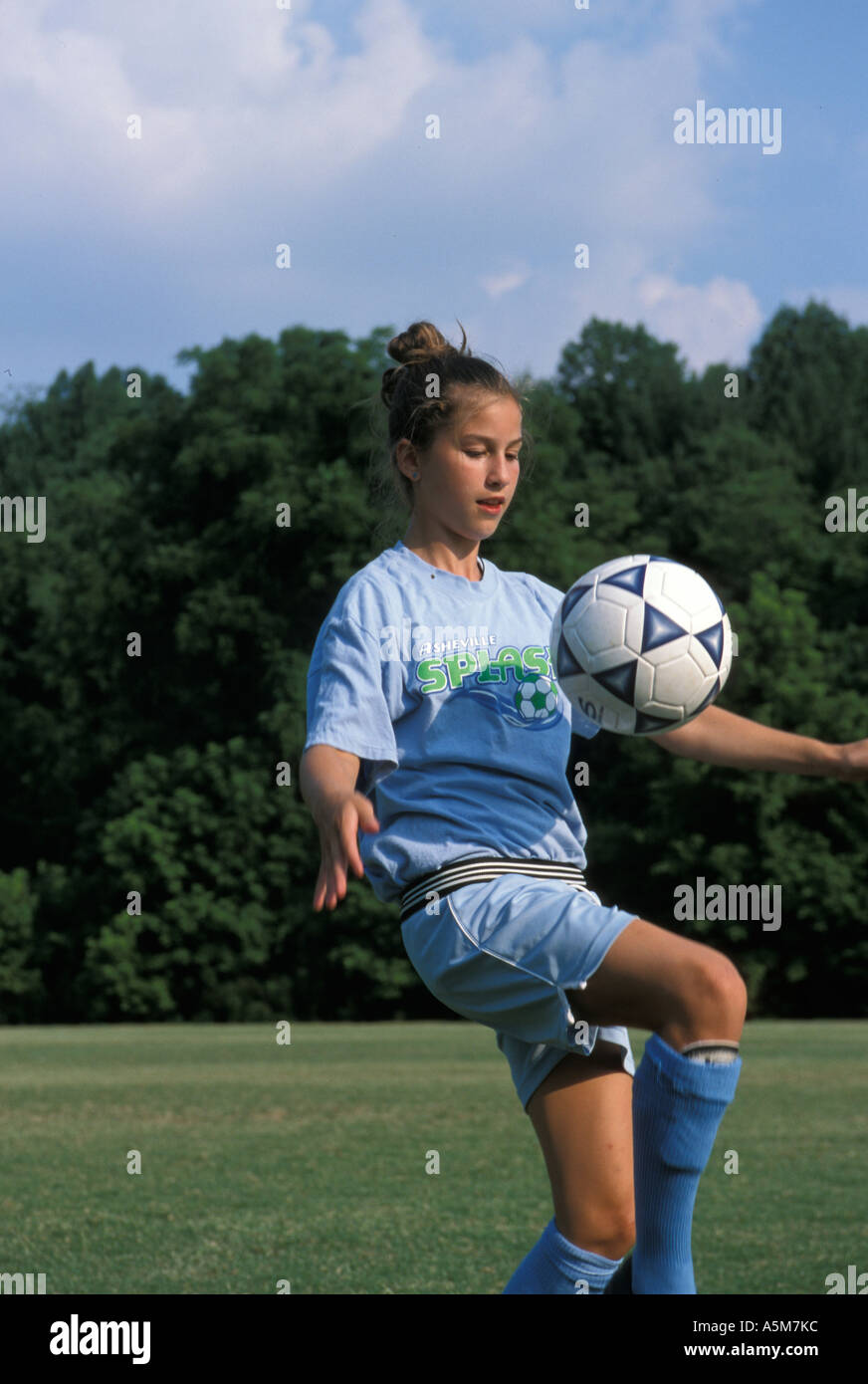 Une fille dans un uniforme de football bleu est un ballon qui rebondit sur  son genou Photo Stock - Alamy