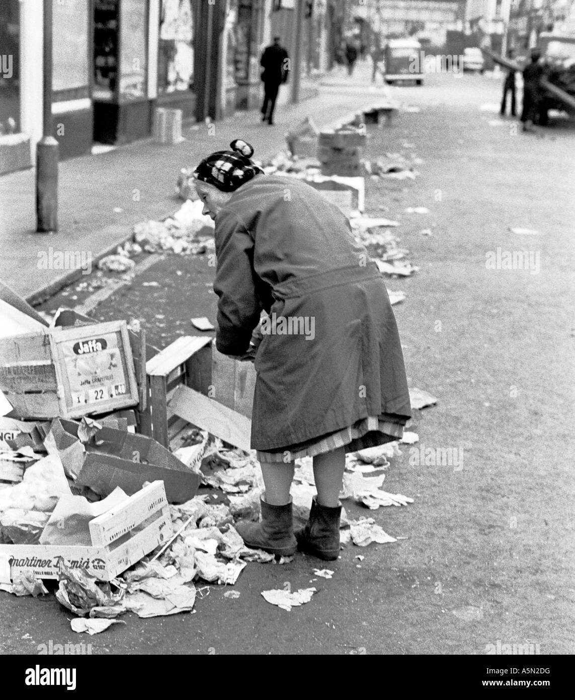 Vieille Femme récupère parmi les ordures pour trouver de la nourriture après le marché de Portobello Road à Londres Notting Hill Gate. 1975. Banque D'Images