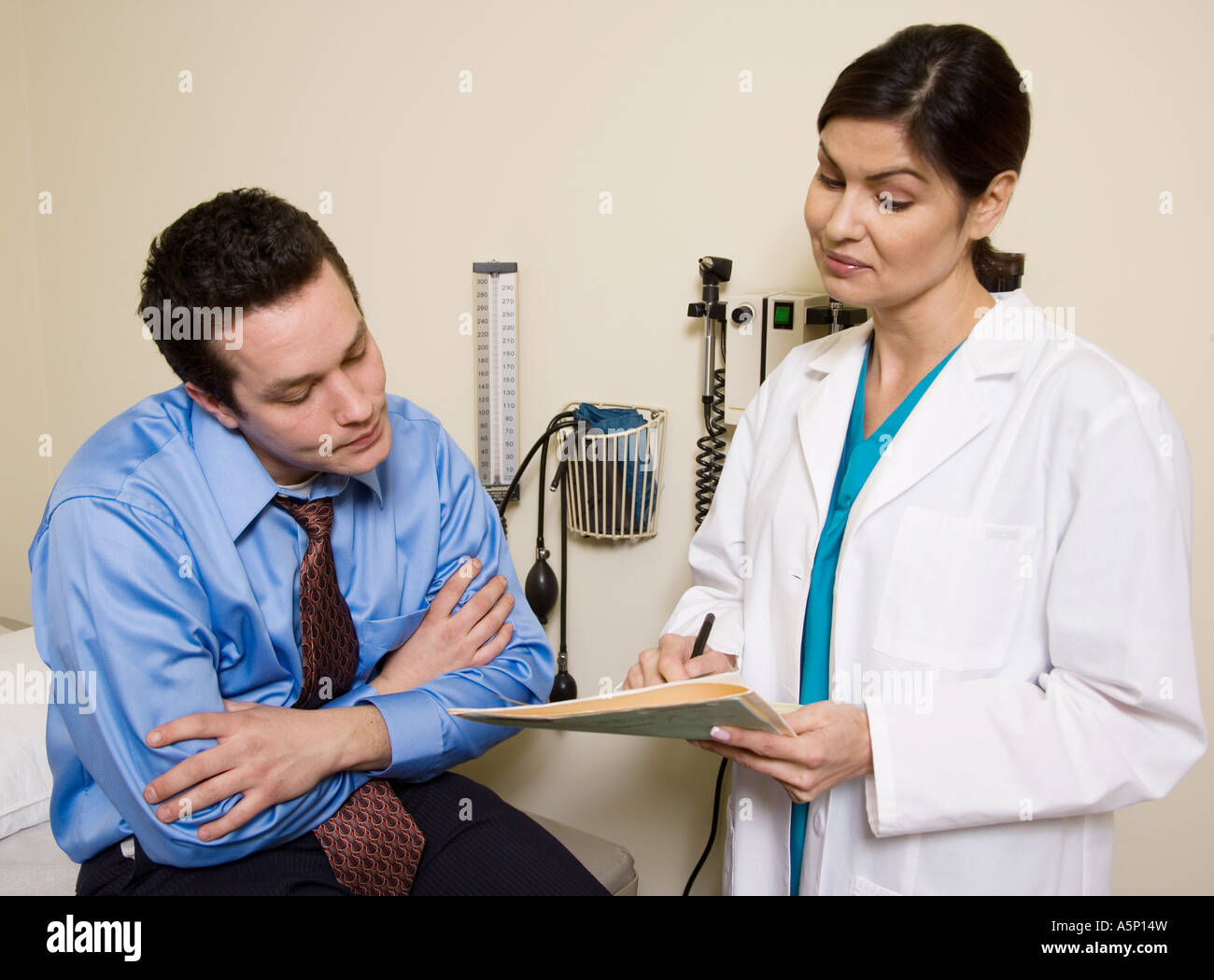 Médecin regarde au-dessus du patient pour lire son histoire médicale. Banque D'Images