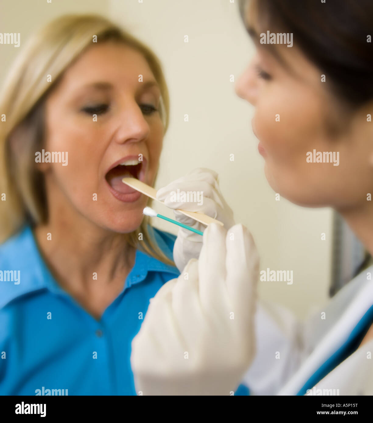 Les écouvillons médecin l'intérieur de bouche du patient pour vérifier si elle a la gorge ou le Dr strept prend un échantillon d'ADN. Banque D'Images