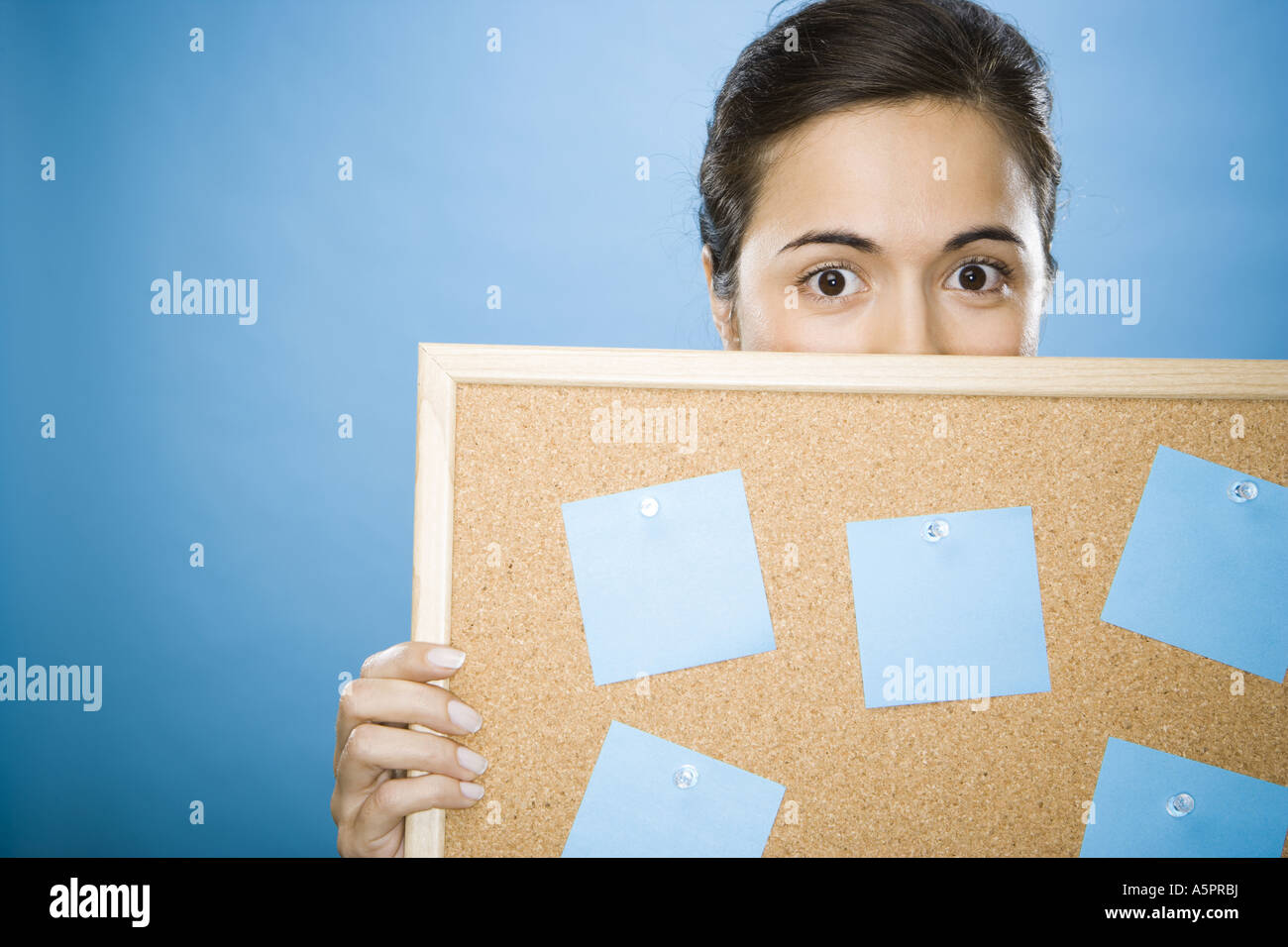 Close-up of a young woman holding a bulletin board contre son visage Banque D'Images