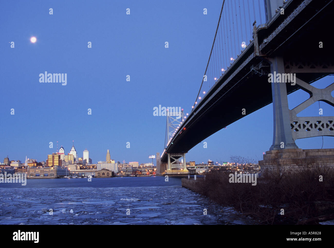Ben Franklin Bridge et Philly skyline avec la lune et Vénus de Camden, NJ sur un matin d'hiver avec l'écoulement de la glace sur le Delaware Banque D'Images