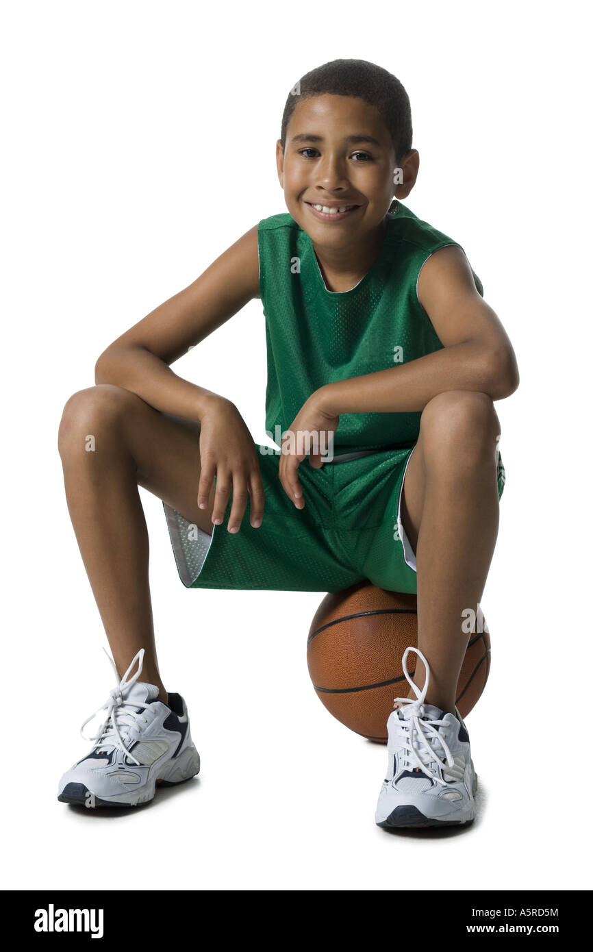 Portrait d'un garçon assis sur un terrain de basket-ball Banque D'Images