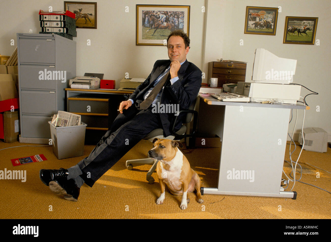 Représentant des bookmakers TOMMY NEWELL PROPRIÉTAIRE DE THOMAS ASHLEY BOOKMAKERS ASSIS DANS SON BUREAU AVEC SON CHIEN Banque D'Images