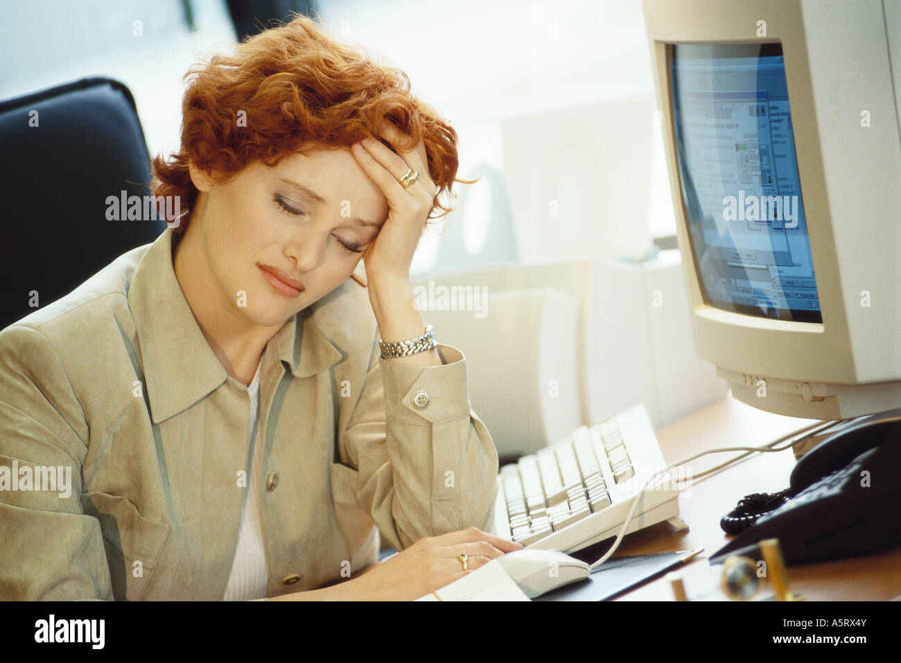 Businesswoman sitting at desk, holding head Banque D'Images