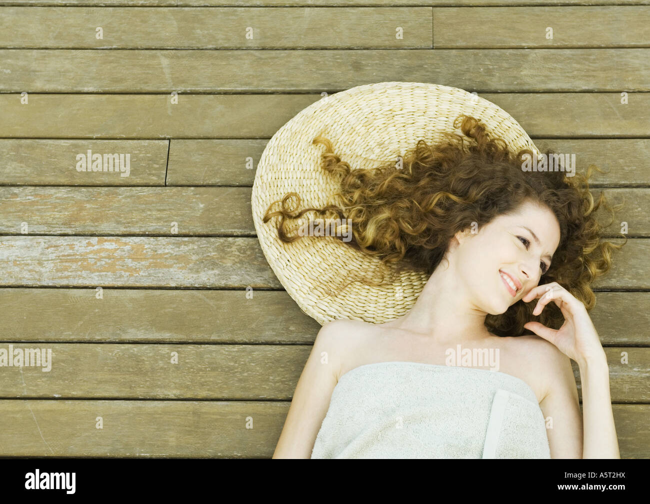 Femme enveloppée dans une serviette, allongé sur le pont, smiling Banque D'Images