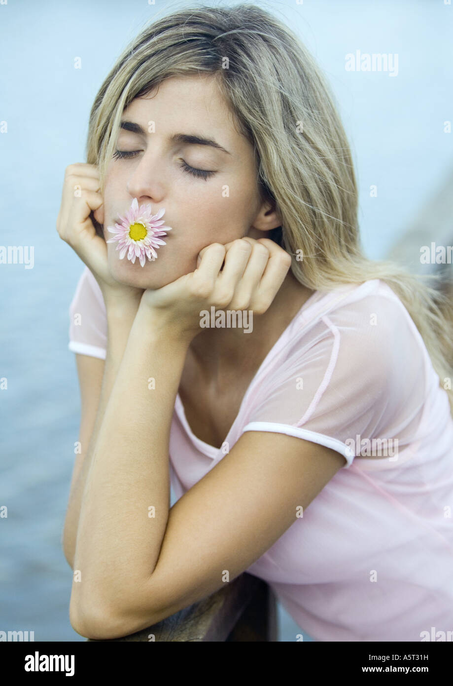 Femme avec une fleur dans la bouche, les yeux fermés Banque D'Images