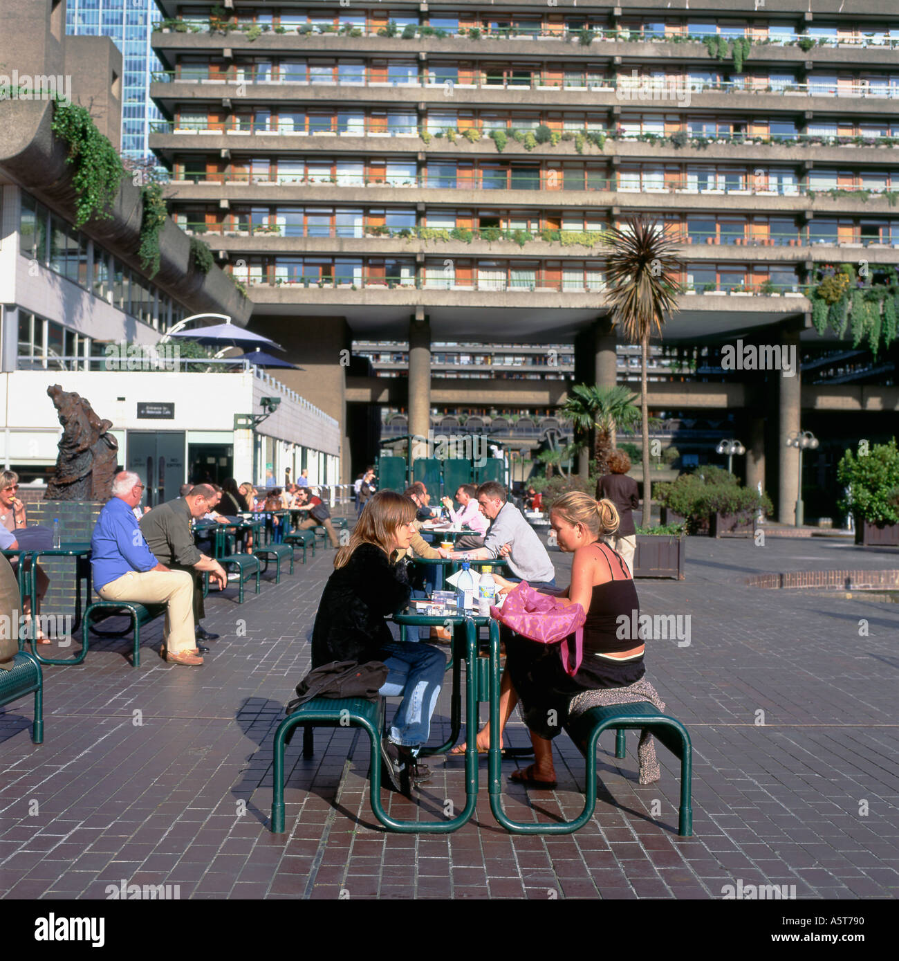 Les gens assis à table pour manger et boire à la terrasse d'un café sur la terrasse au bord du lac en été au Barbican Centre London UK KATHY DEWITT Banque D'Images