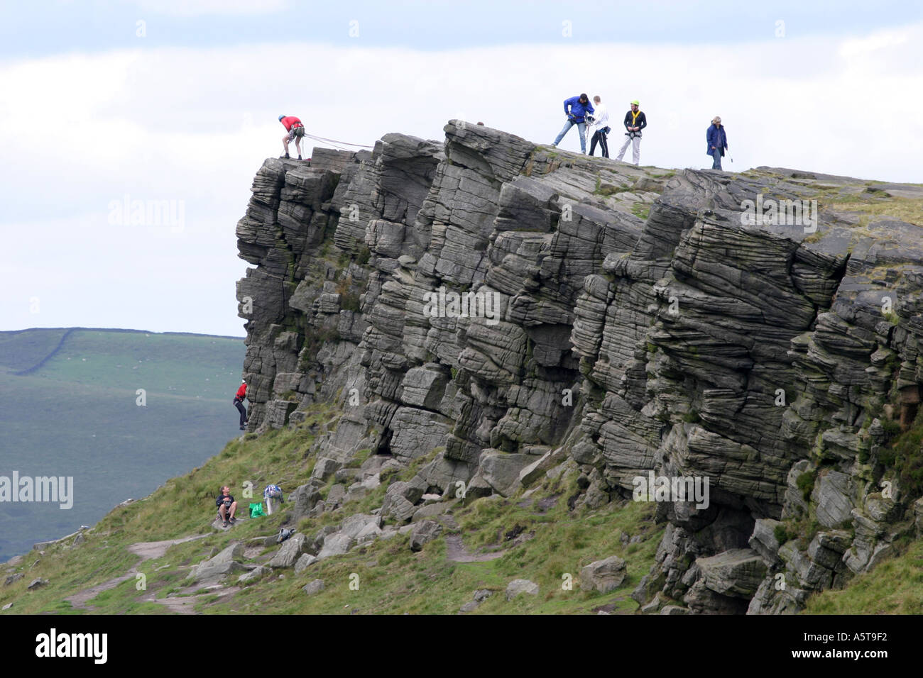 Alpinistes sur Windgather rochers sur le côté est du Peak District, Derbyshire, Angleterre. L'homme au haut des rochers est l'assurage d'un grimpeur sur le chemin vers le haut. Banque D'Images
